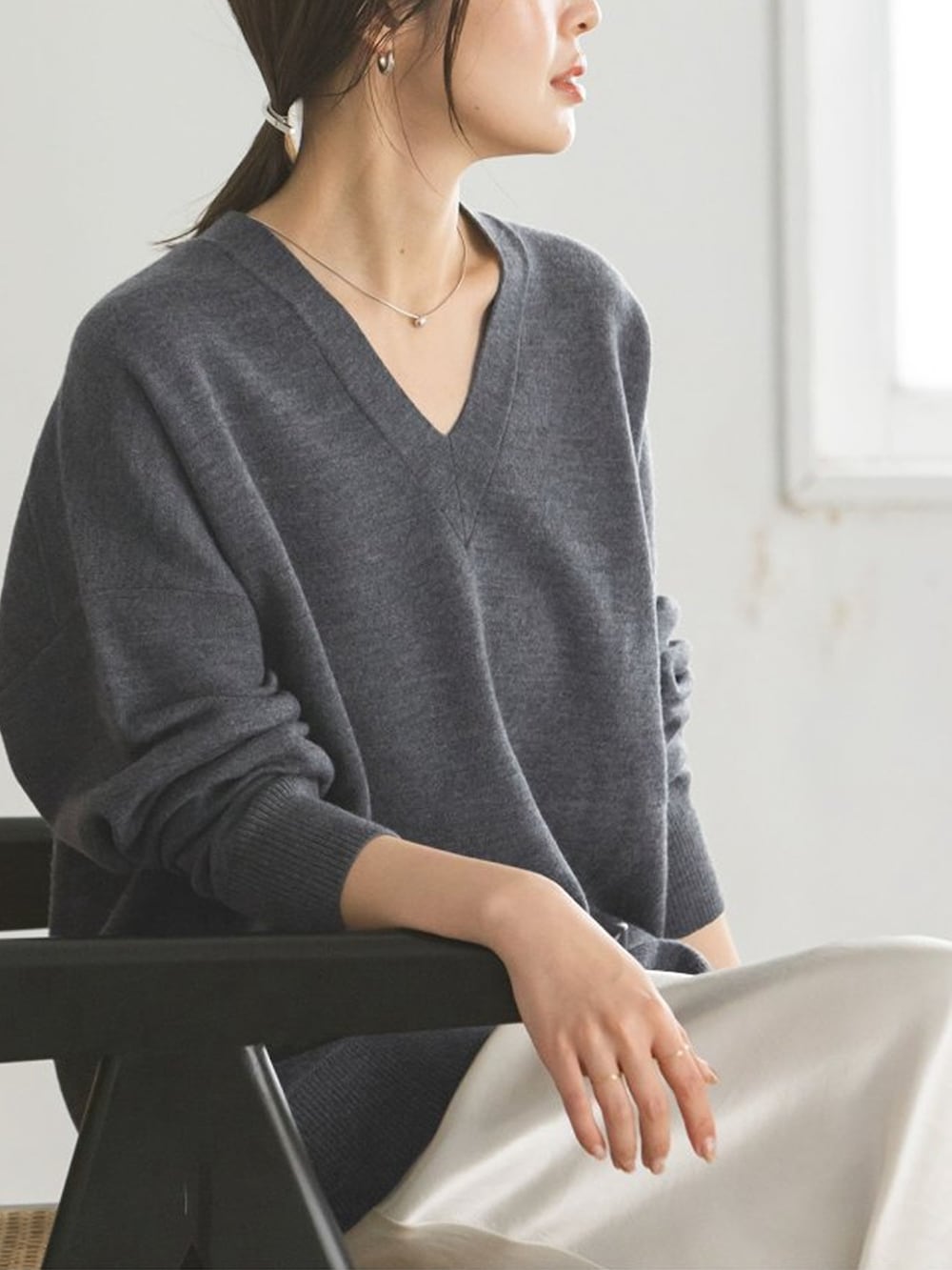 グレー系のニット/セーター、ホワイト系のスカートを着用したレディースの秋コーディネートの4枚目の写真