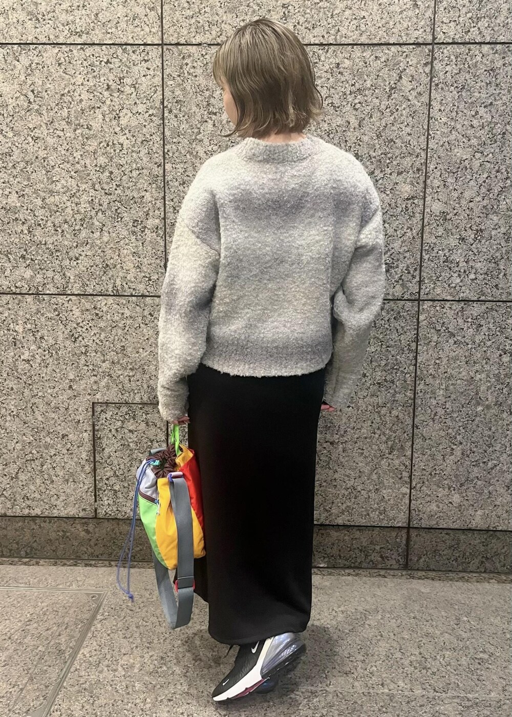 グレー系のニット/セーター、ブラック系のスカート、ブラック系のスニーカーを着用したレディースの冬コーディネートの2枚目の写真