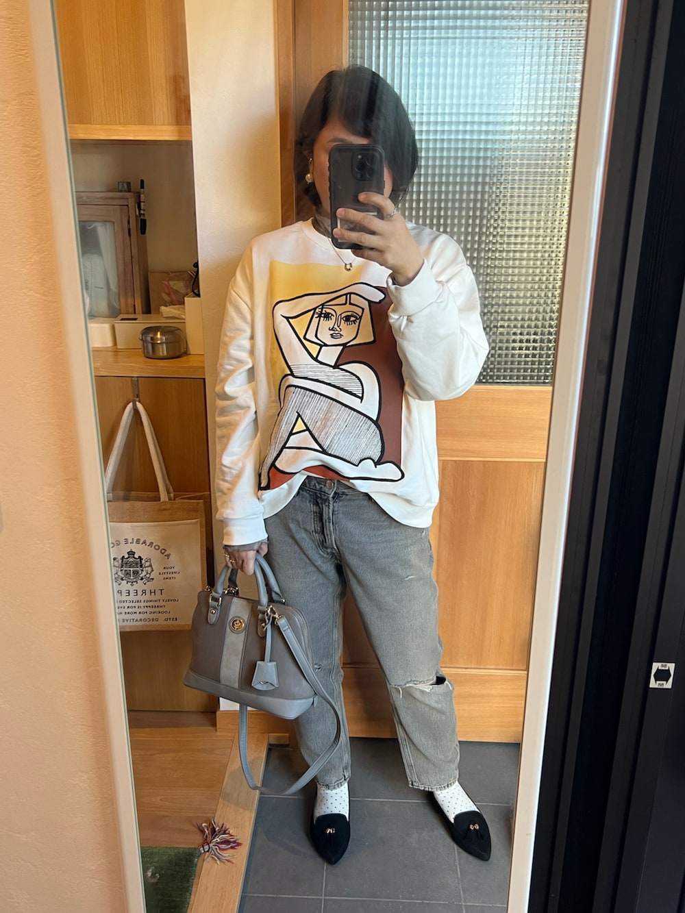 グレー系のデニムパンツ、ホワイト系のスウェット、グレー系のTシャツ/カットソーを着用したレディースの冬コーディネートの2枚目の写真