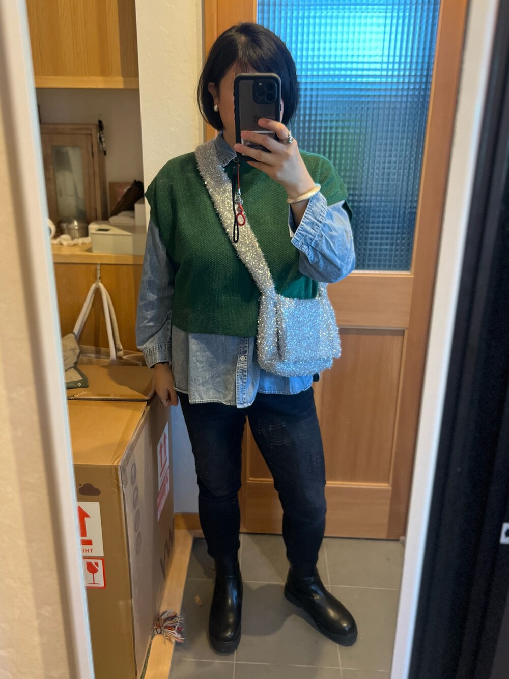 ブラック系のデニムパンツ、ブラック系のブーツ、シルバー系のショルダーバッグを着用したレディースの冬コーディネートの2枚目の写真