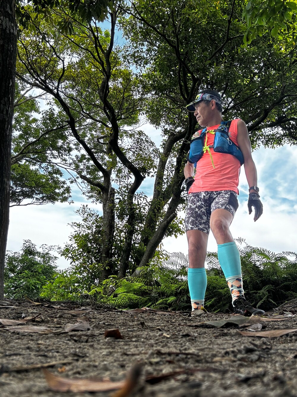 オレンジ系のTシャツ/カットソー、ブラック系のシューズ、シルバー系のレギンス/スパッツを着用したメンズの夏コーディネートの2枚目の写真