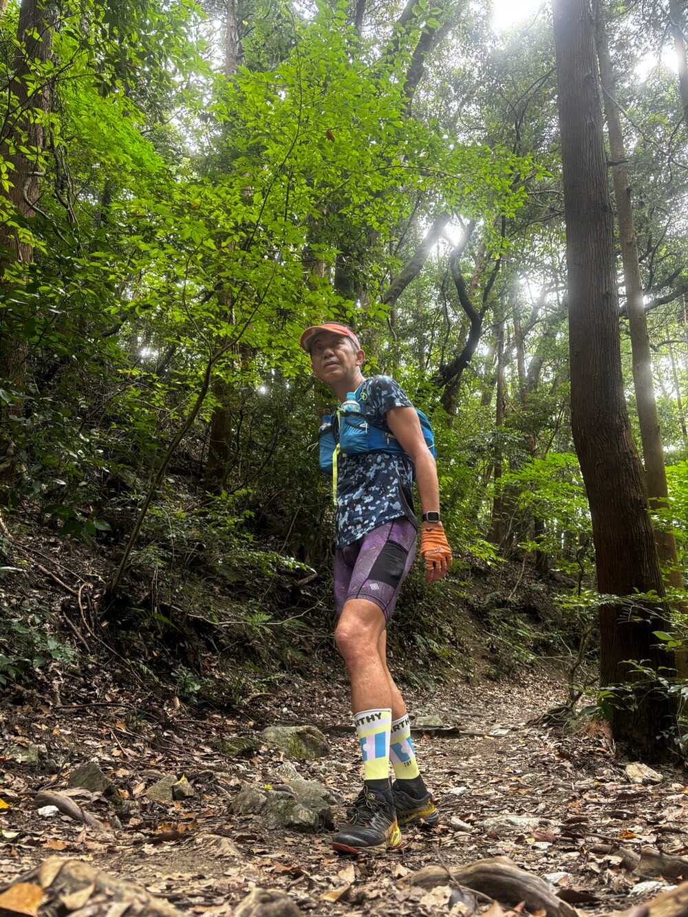 ブルー系のトップス、ブルー系のバックパック/リュック、パープル系のレギンス/スパッツを着用したメンズの夏コーディネートの3枚目の写真