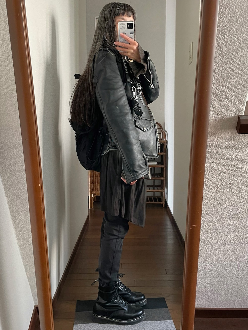 グリーン系のチュニック、ブラック系のブーツ、ブラック系のライダースジャケットを着用したレディースの秋コーディネートの2枚目の写真