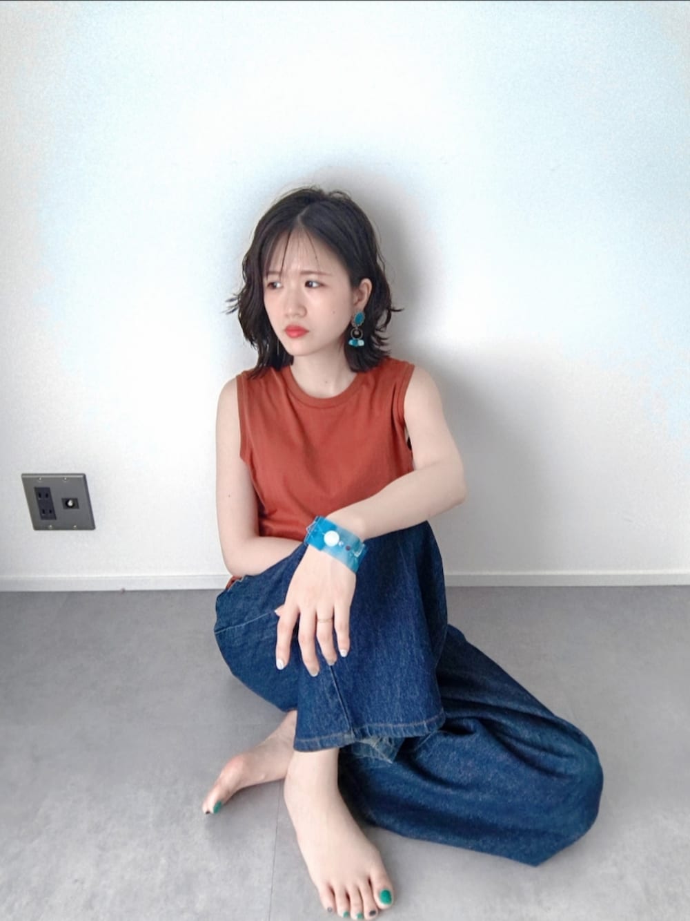 ブルー系のデニムパンツ、ブラック系のサンダル、オレンジ系のタンクトップを着用したレディースの夏コーディネートの5枚目の写真