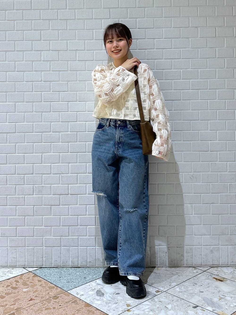 ブラック系のスニーカー、ブルー系のデニムパンツ、ホワイト系のカーディガン/ボレロを着用したレディースの春コーディネートの4枚目の写真