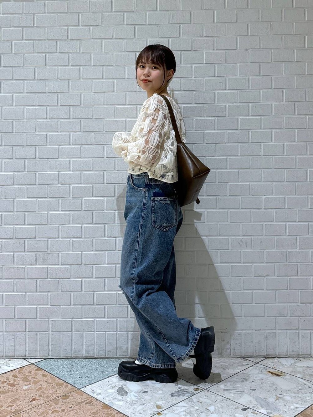 ブラック系のスニーカー、ブルー系のデニムパンツ、ホワイト系のカーディガン/ボレロを着用したレディースの春コーディネートの2枚目の写真