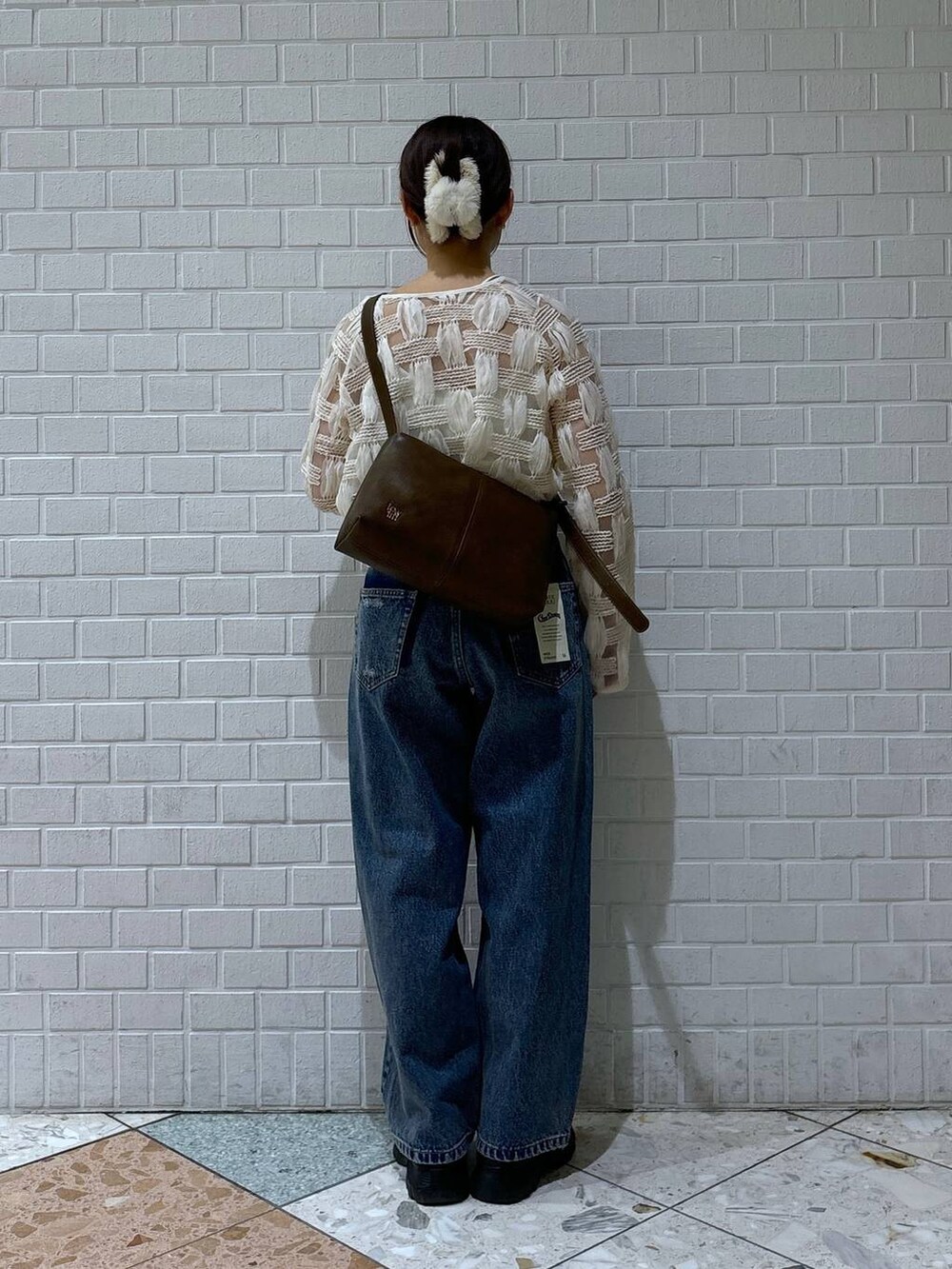 ブラック系のスニーカー、ブルー系のデニムパンツ、ホワイト系のカーディガン/ボレロを着用したレディースの春コーディネートの3枚目の写真