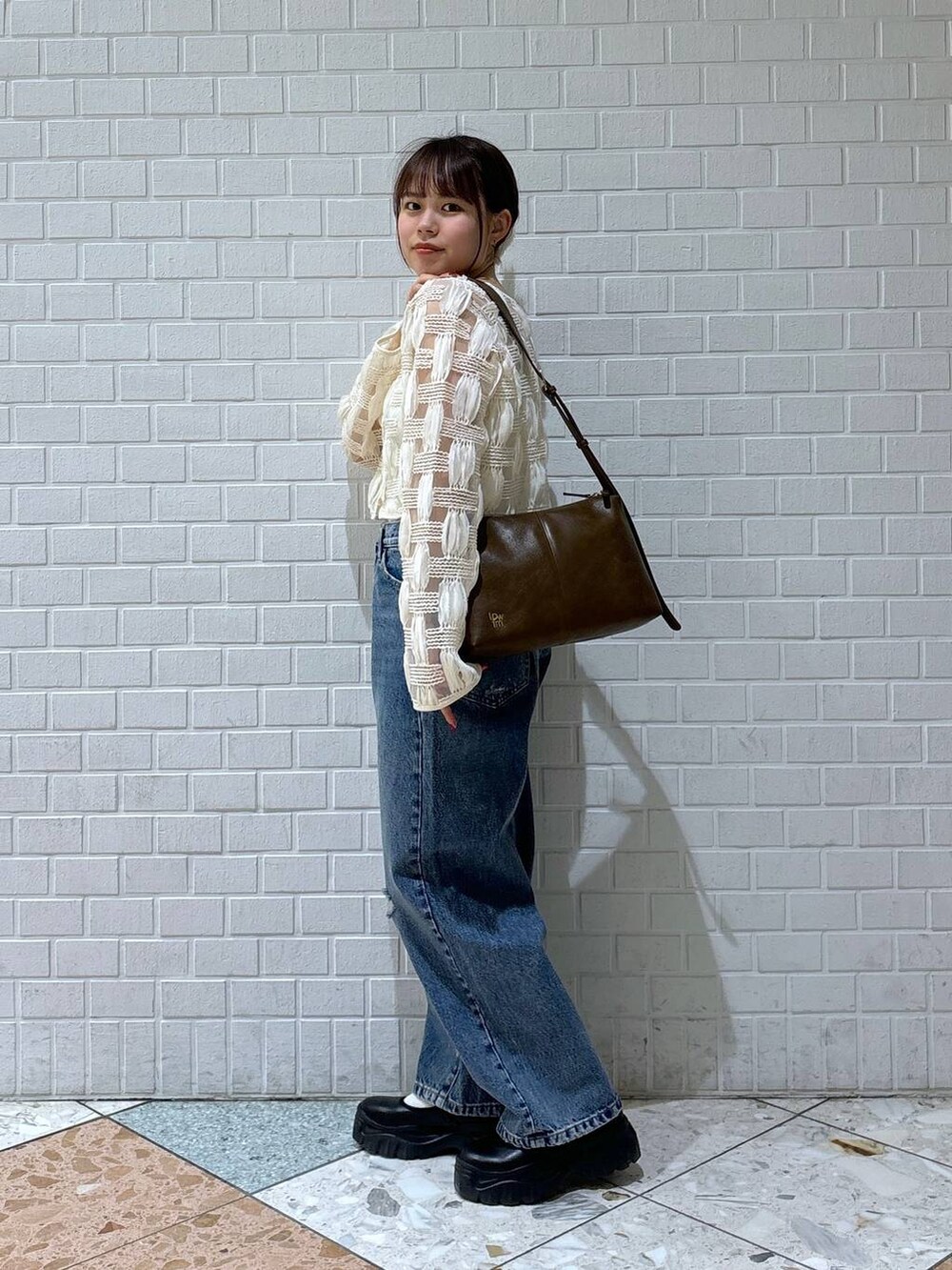 ブラック系のスニーカー、ブルー系のデニムパンツ、ホワイト系のカーディガン/ボレロを着用したレディースの春コーディネートの6枚目の写真