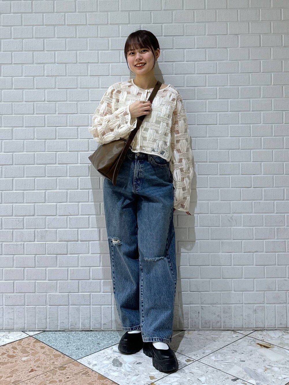 ブラック系のスニーカー、ブルー系のデニムパンツ、ホワイト系のカーディガン/ボレロを着用したレディースの春コーディネートの5枚目の写真