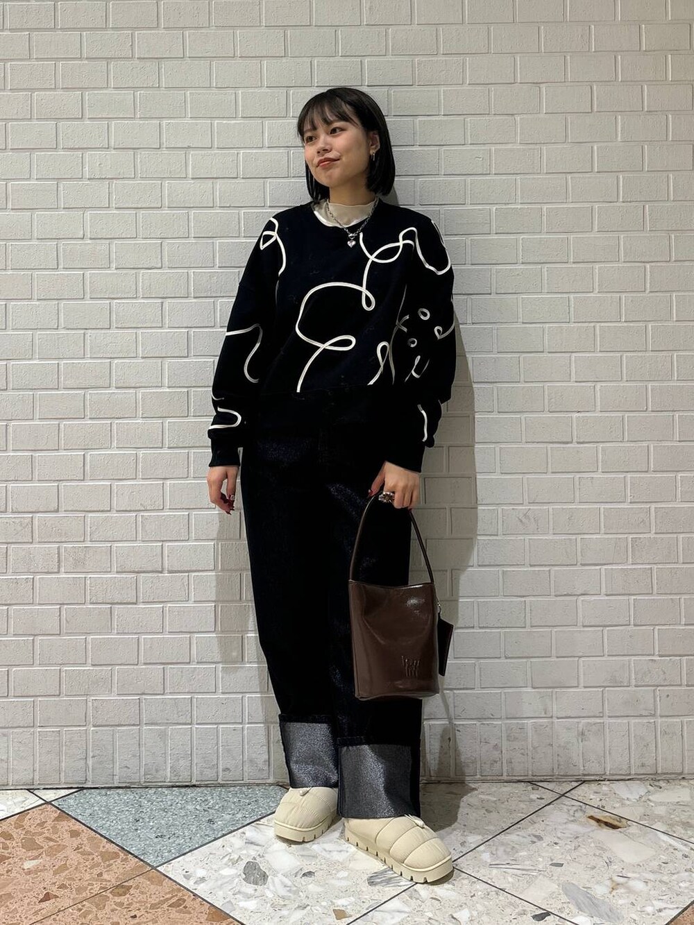 ブラック系のデニムパンツ、ホワイト系のブーツ、ブラック系のスウェットを着用したレディースの冬コーディネートの4枚目の写真