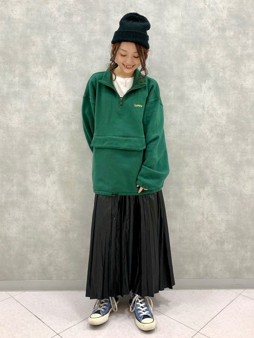 グリーン系のパーカー、ブラック系のスカートを着用したレディースの秋コーディネートの2枚目の写真