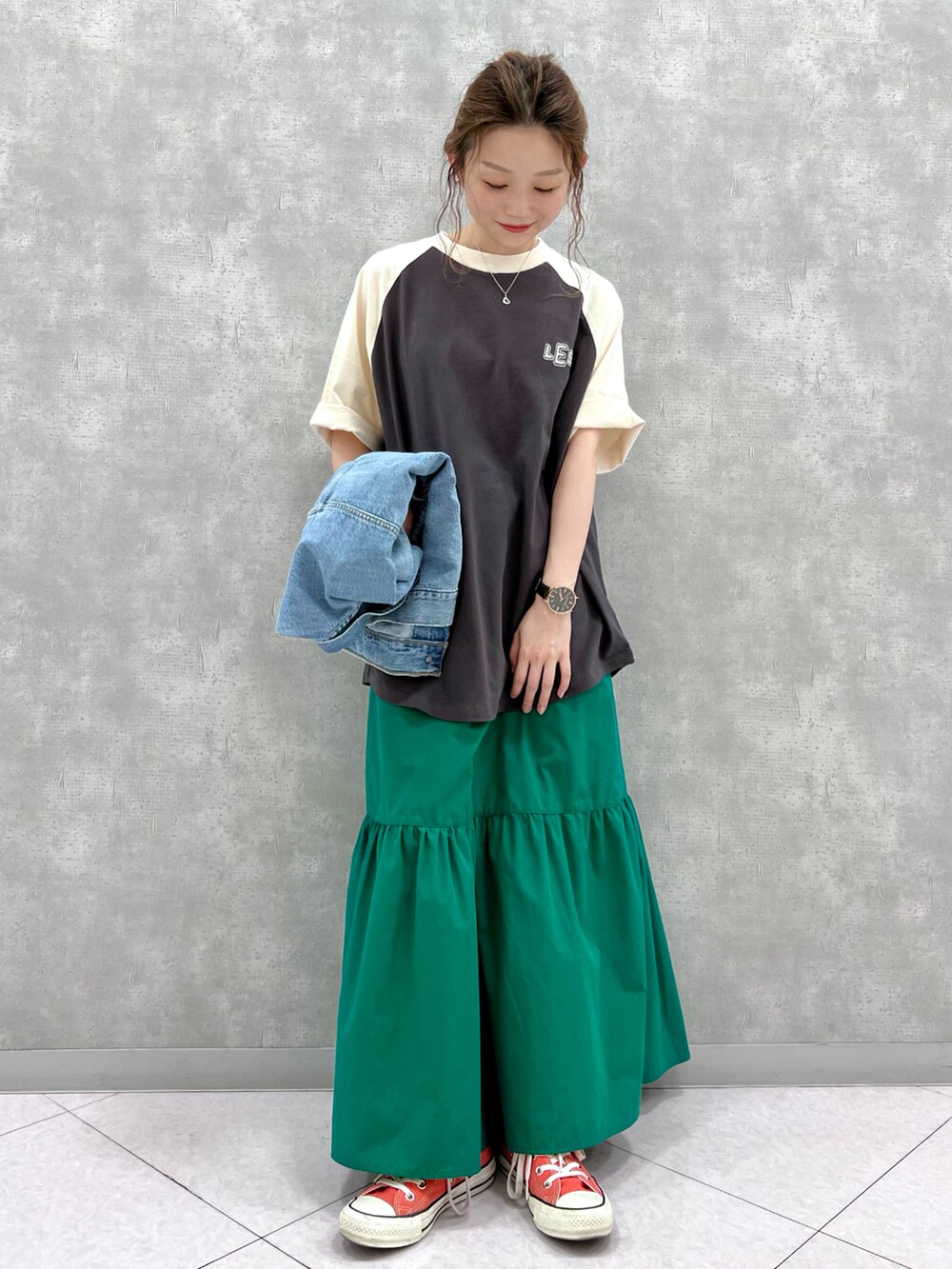 グリーン系のスカート、オレンジ系のスニーカー、ブラック系のTシャツ/カットソーを着用したレディースの春コーディネートの2枚目の写真