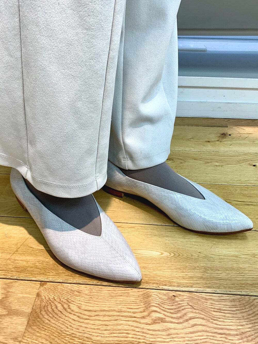 ホワイト系のパンプス、グレー系のパンツ、パープル系のカーディガン/ボレロを着用したレディースの冬コーディネートの2枚目の写真