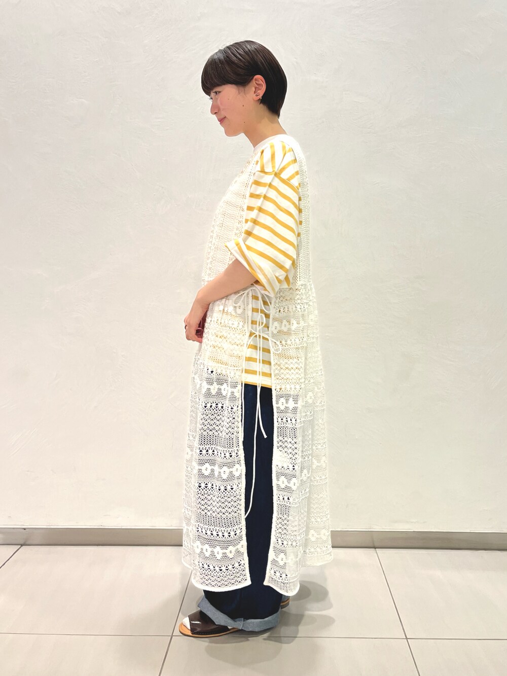 ホワイト系のワンピース、イエロー系のTシャツ/カットソー、ブルー系のデニムパンツを着用したレディースの春コーディネートの2枚目の写真