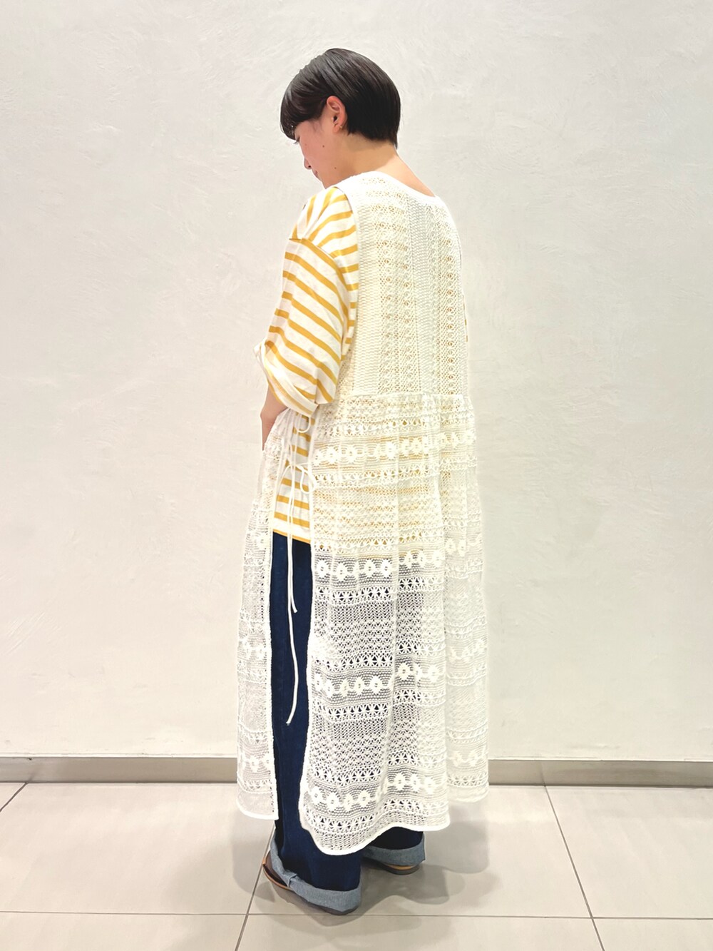 ホワイト系のワンピース、イエロー系のTシャツ/カットソー、ブルー系のデニムパンツを着用したレディースの春コーディネートの3枚目の写真