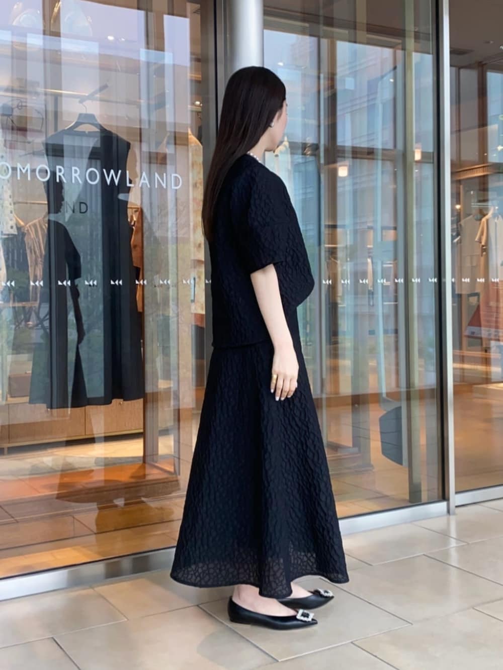 ブラック系のパンプス、ブラック系のシャツ/ブラウス、ブラック系のスカートを着用したレディースの春コーディネートの2枚目の写真