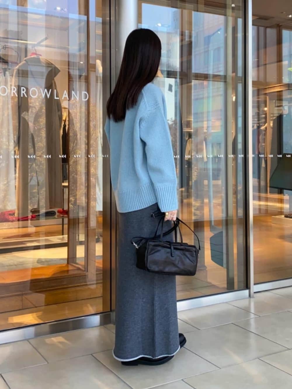 ブラック系のショルダーバッグ、ブラック系のブーツ、グレー系のスカートを着用したレディースの秋コーディネートの3枚目の写真