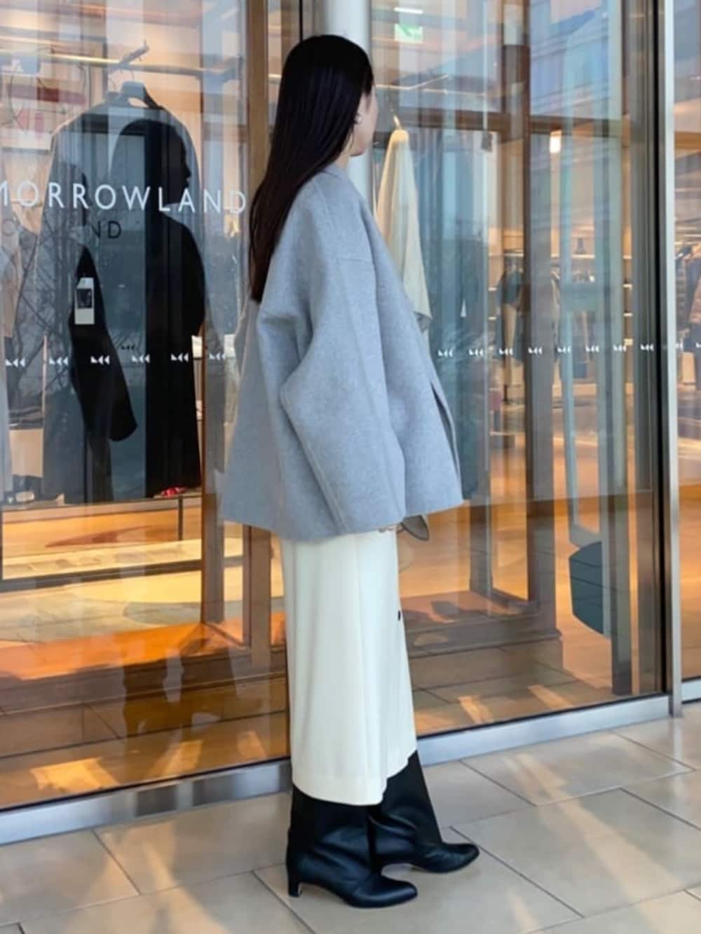 ブラック系のブーツ、グレー系のその他アウター、ブルー系のニット/セーターを着用したレディースの冬コーディネートの2枚目の写真