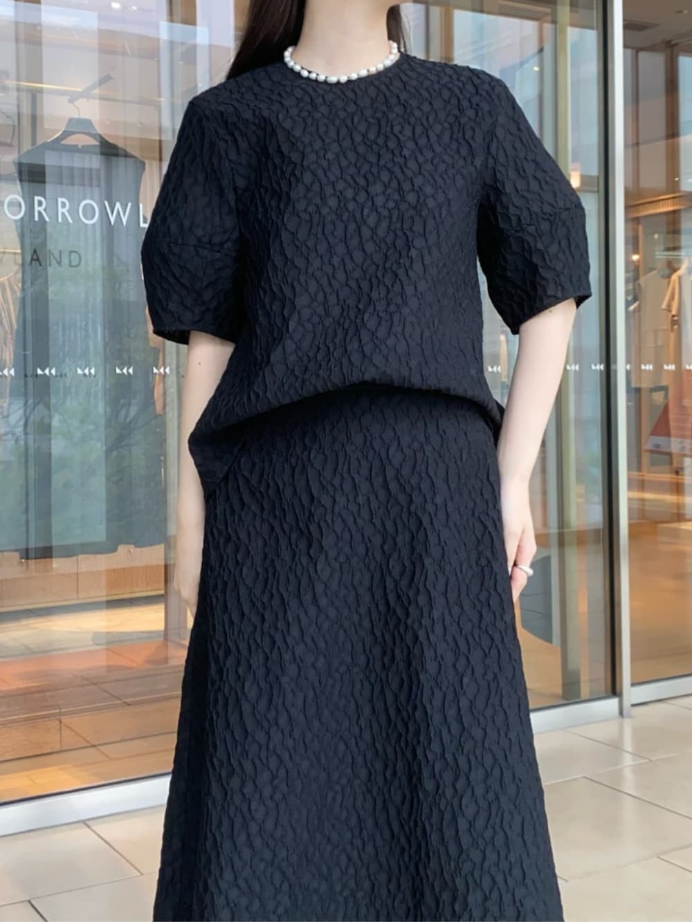 ブラック系のパンプス、ブラック系のシャツ/ブラウス、ブラック系のスカートを着用したレディースの春コーディネートの3枚目の写真