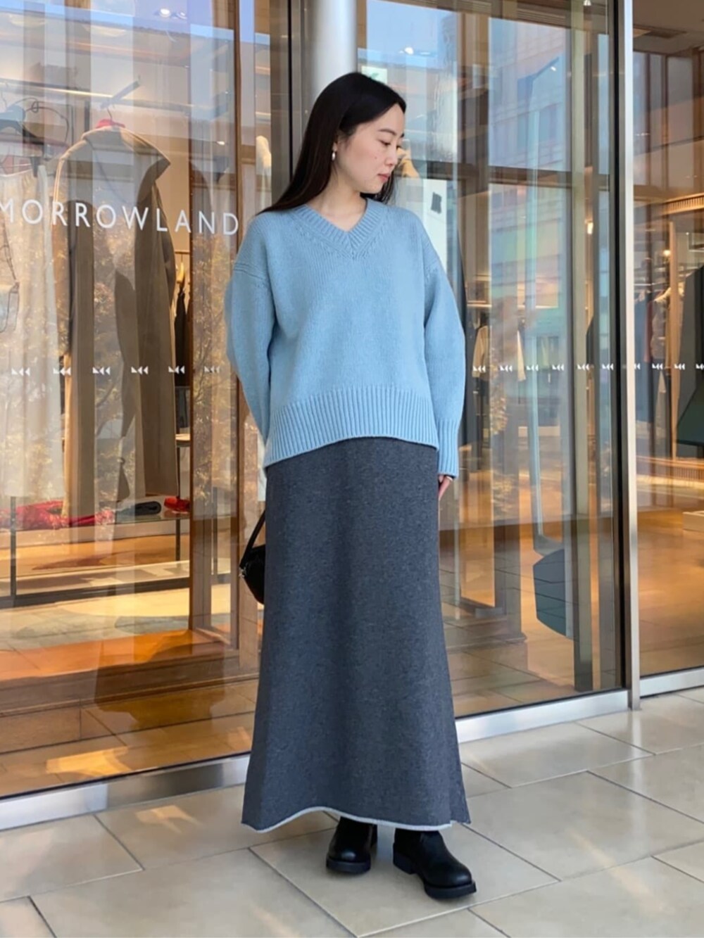 ブラック系のショルダーバッグ、ブラック系のブーツ、グレー系のスカートを着用したレディースの秋コーディネートの2枚目の写真