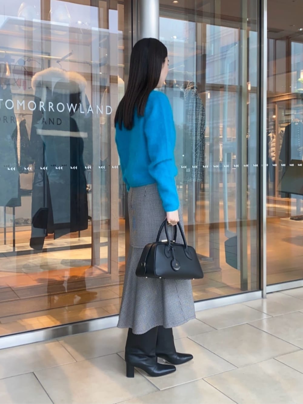 ブラック系のショルダーバッグ、ブラック系のスカート、ブルー系のカーディガン/ボレロを着用したレディースの秋コーディネートの3枚目の写真