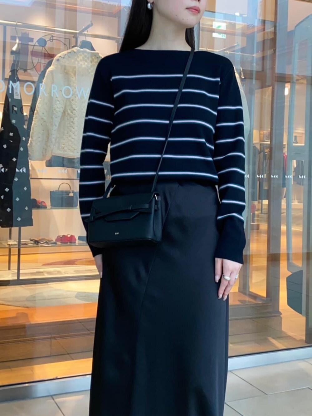 ブラック系のショルダーバッグ、ブラック系のブーツ、ブルー系のニット/セーターを着用したレディースの秋コーディネートの4枚目の写真