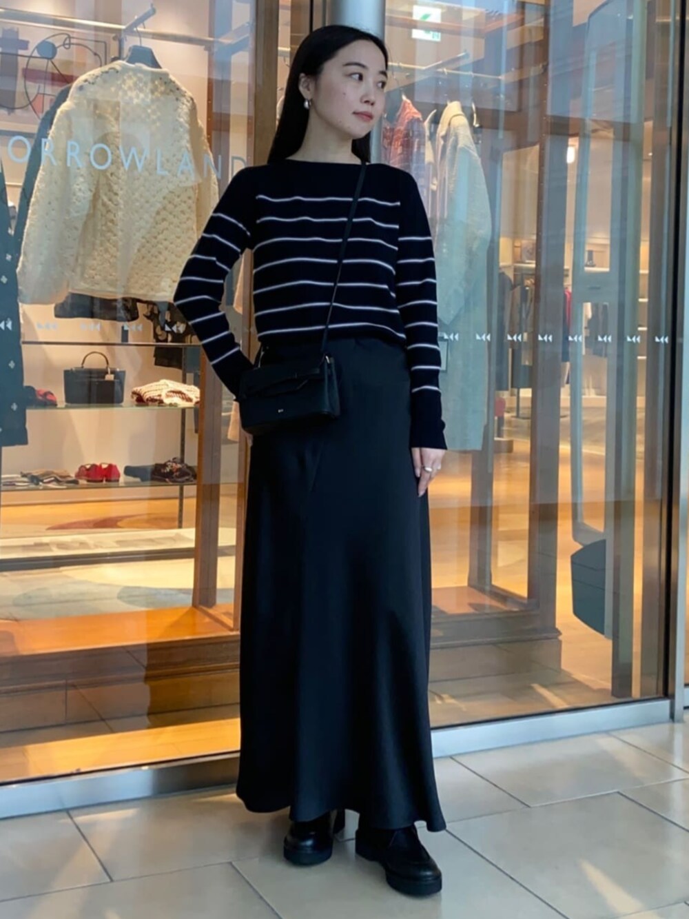 ブラック系のショルダーバッグ、ブラック系のブーツ、ブルー系のニット/セーターを着用したレディースの秋コーディネートの2枚目の写真