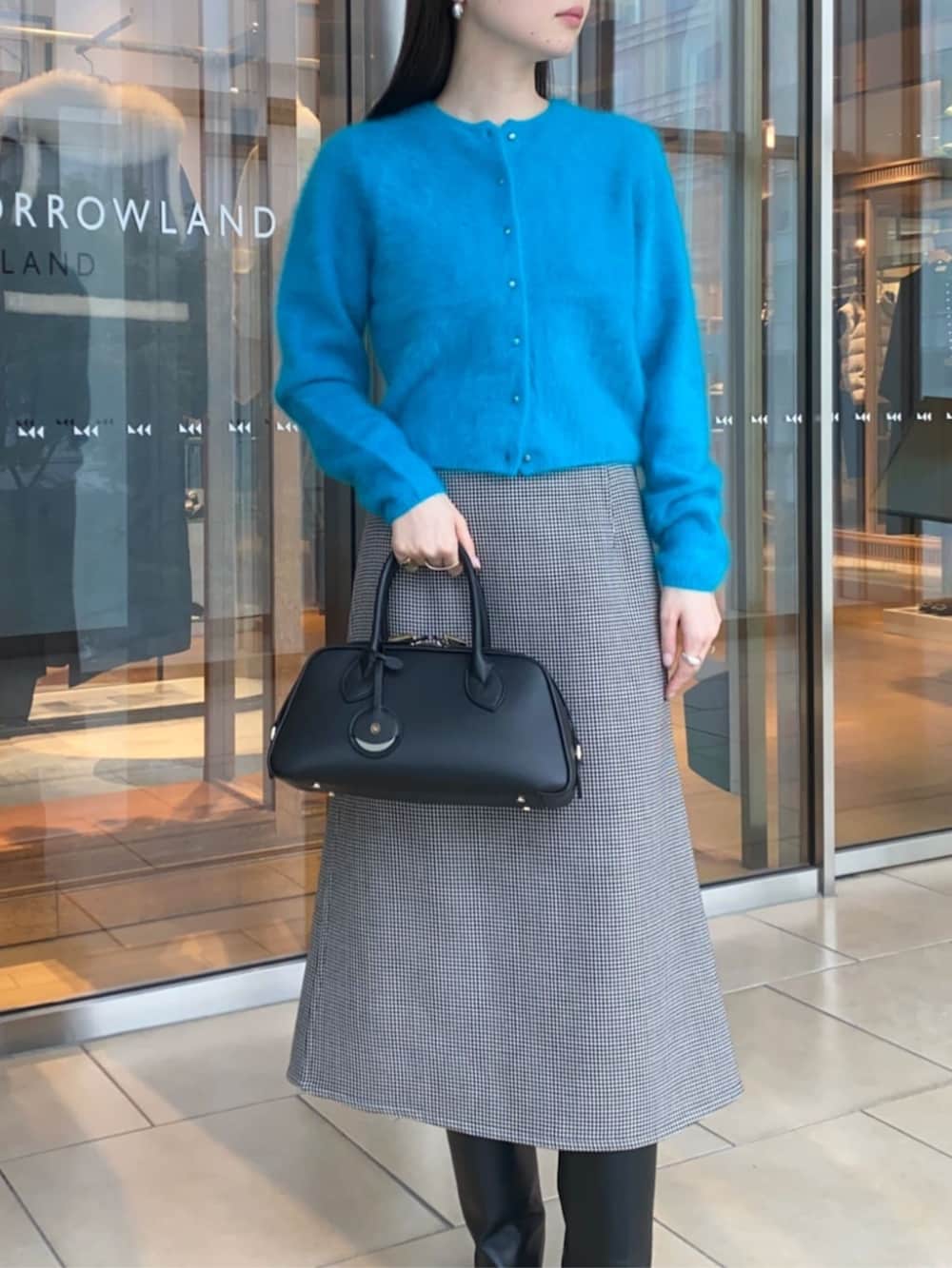 ブラック系のショルダーバッグ、ブラック系のスカート、ブルー系のカーディガン/ボレロを着用したレディースの秋コーディネートの4枚目の写真