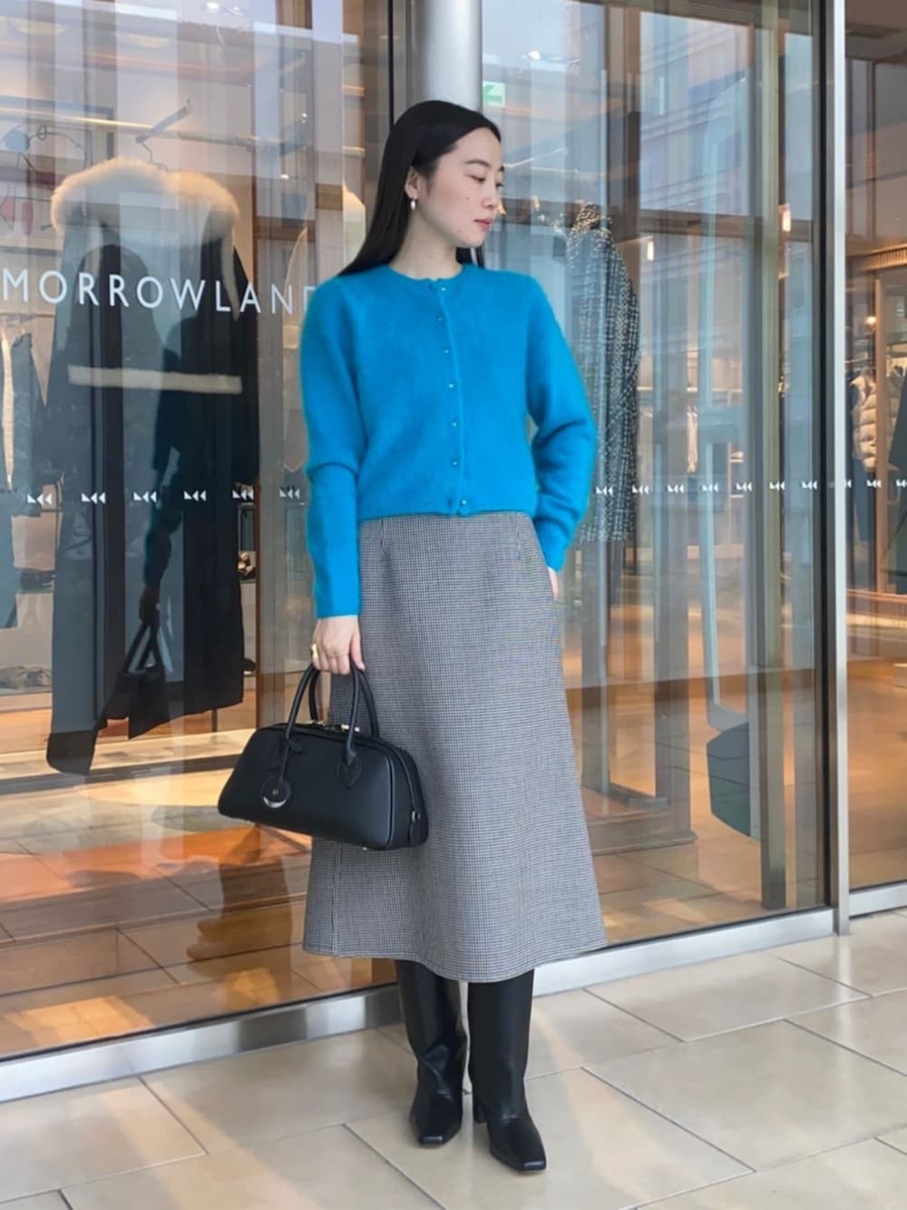 ブラック系のショルダーバッグ、ブラック系のスカート、ブルー系のカーディガン/ボレロを着用したレディースの秋コーディネートの2枚目の写真
