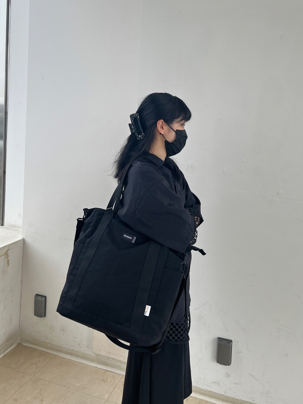 ブラック系のトートバッグを着用したレディースの夏コーディネートの2枚目の写真