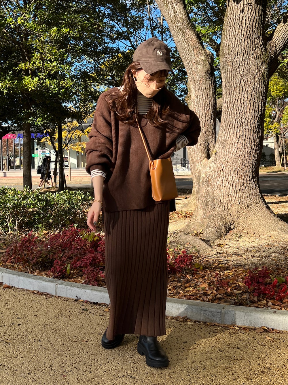 ブラウン系のスカート、ブラウン系のニット/セーター、ホワイト系のニット/セーターを着用したレディースの冬コーディネートの2枚目の写真