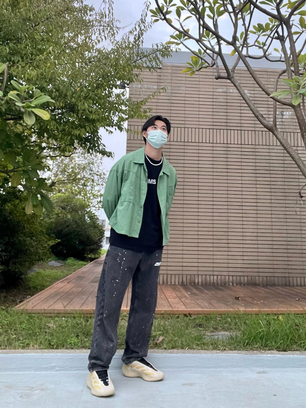 ブラック系のデニムパンツ、ブラック系のTシャツ/カットソー、グリーン系のブルゾンを着用したメンズの秋コーディネートの4枚目の写真