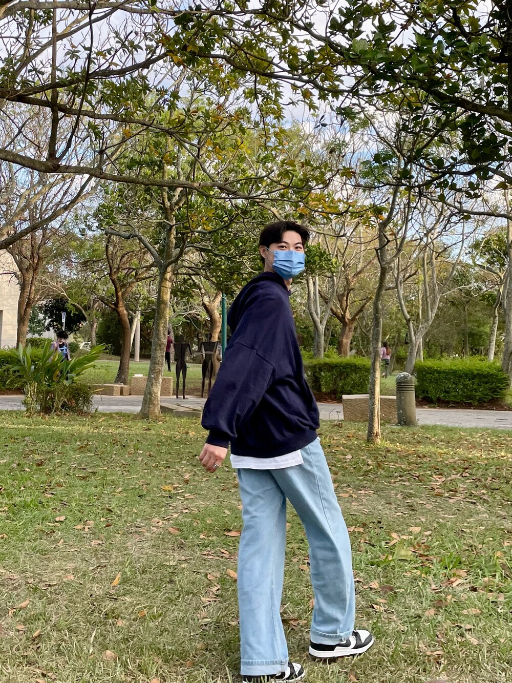 ブルー系のデニムパンツ、ブラック系のスニーカー、ブルー系のパーカーを着用したメンズの秋コーディネートの3枚目の写真