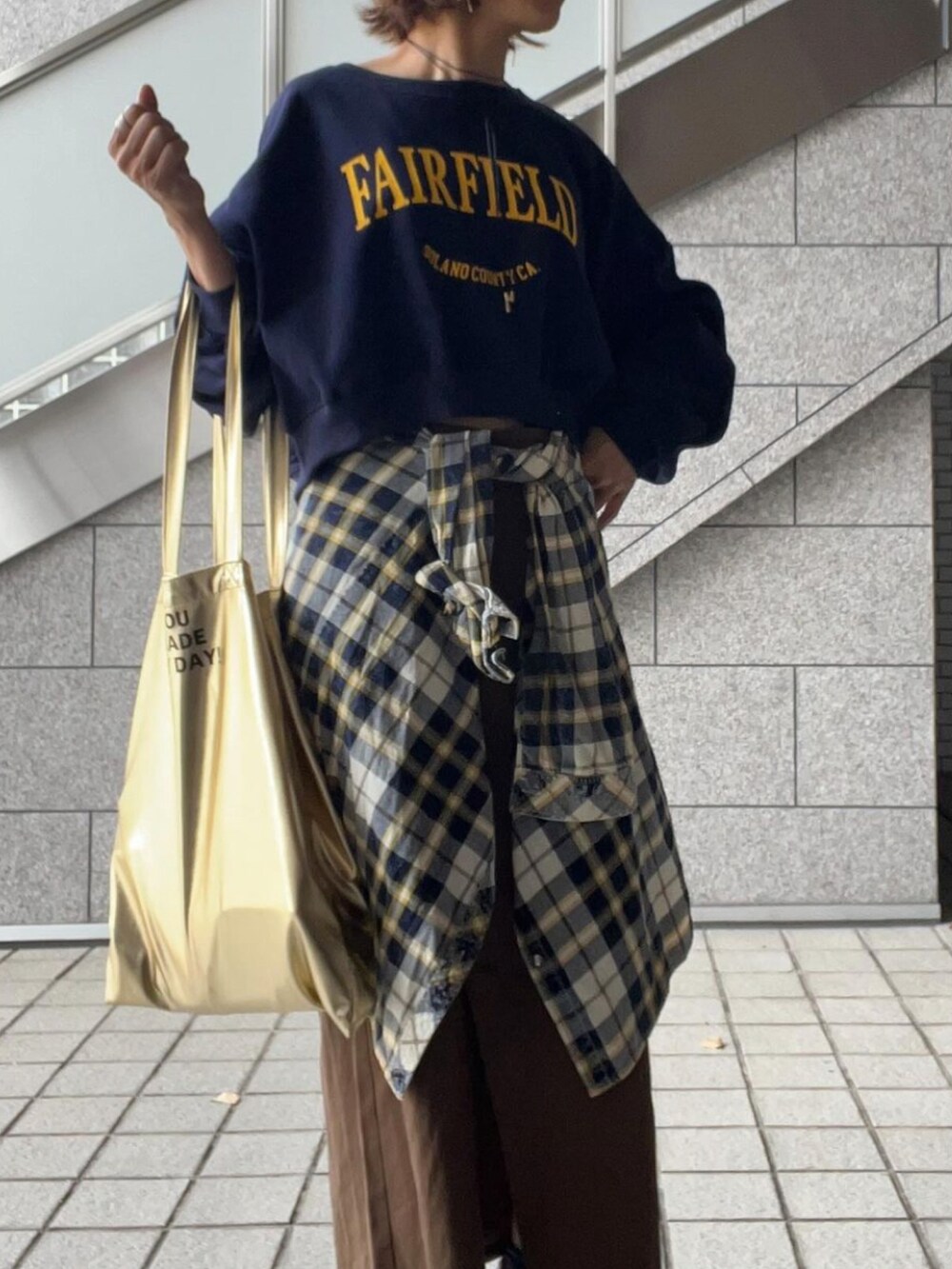 ブルー系のスウェット、ホワイト系のシャツ/ブラウス、ゴールド系のトートバッグを着用したレディースの秋コーディネートの2枚目の写真