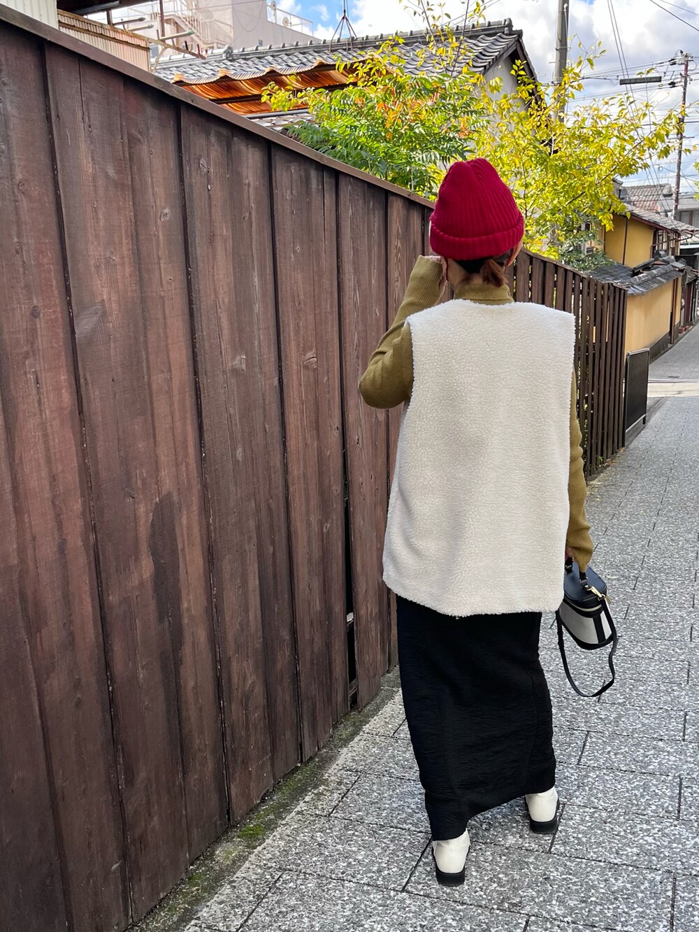 ブラック系のワンピース、グリーン系のニット/セーター、ホワイト系のブーツを着用したレディースの秋コーディネートの2枚目の写真