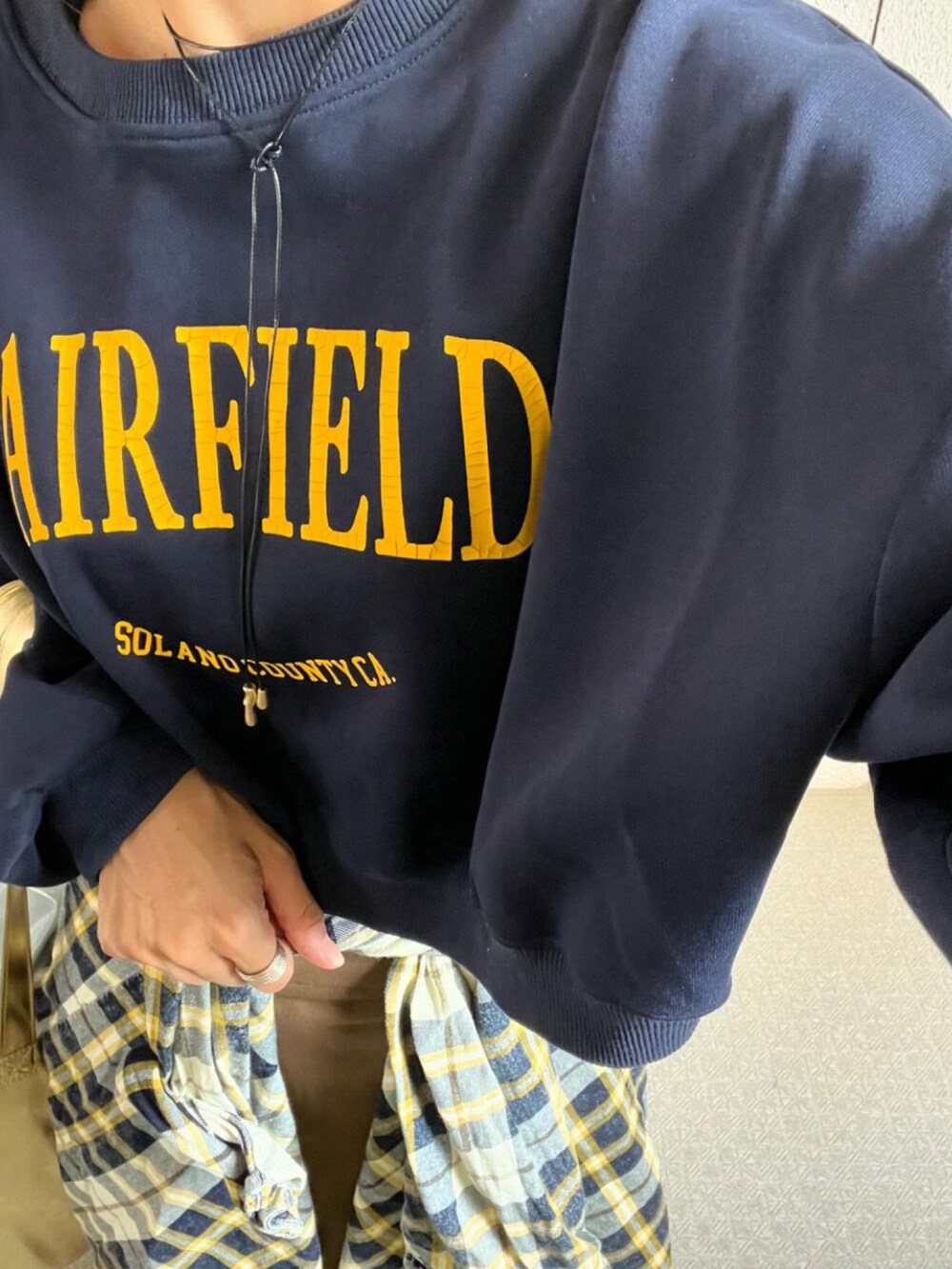 ブルー系のスウェット、ホワイト系のシャツ/ブラウス、ゴールド系のトートバッグを着用したレディースの秋コーディネートの3枚目の写真