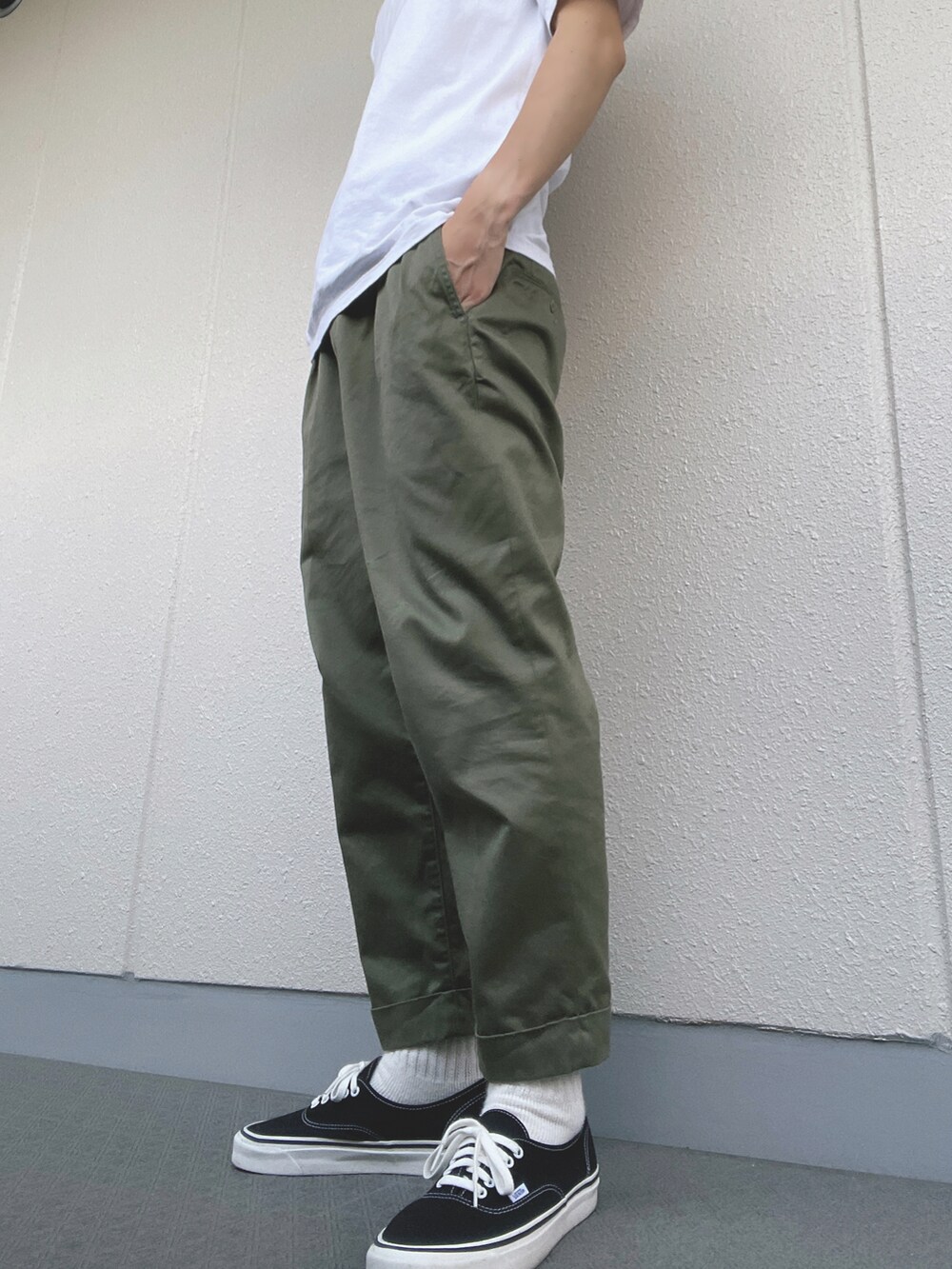 グリーン系のチノパンツ、ブラック系のスニーカー、ホワイト系のTシャツ/カットソーを着用したメンズの夏コーディネートの3枚目の写真