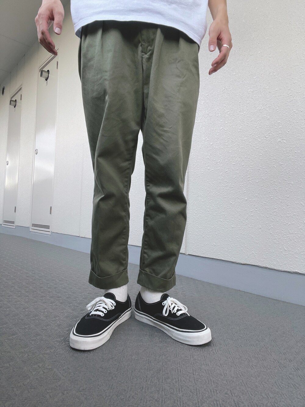 グリーン系のチノパンツ、ブラック系のスニーカー、ホワイト系のTシャツ/カットソーを着用したメンズの夏コーディネートの4枚目の写真