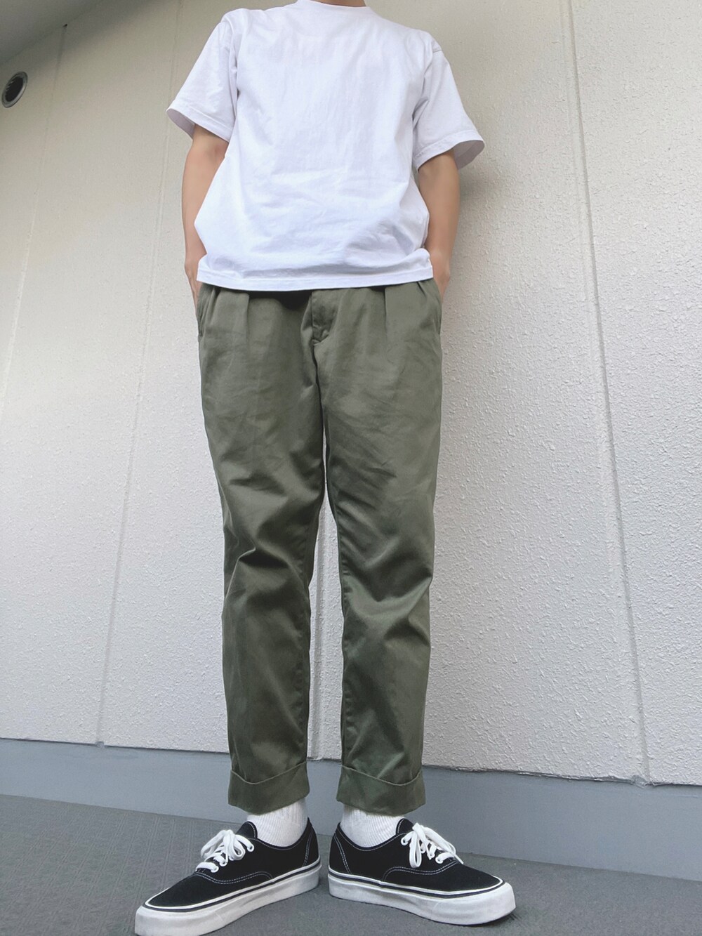 グリーン系のチノパンツ、ブラック系のスニーカー、ホワイト系のTシャツ/カットソーを着用したメンズの夏コーディネートの2枚目の写真