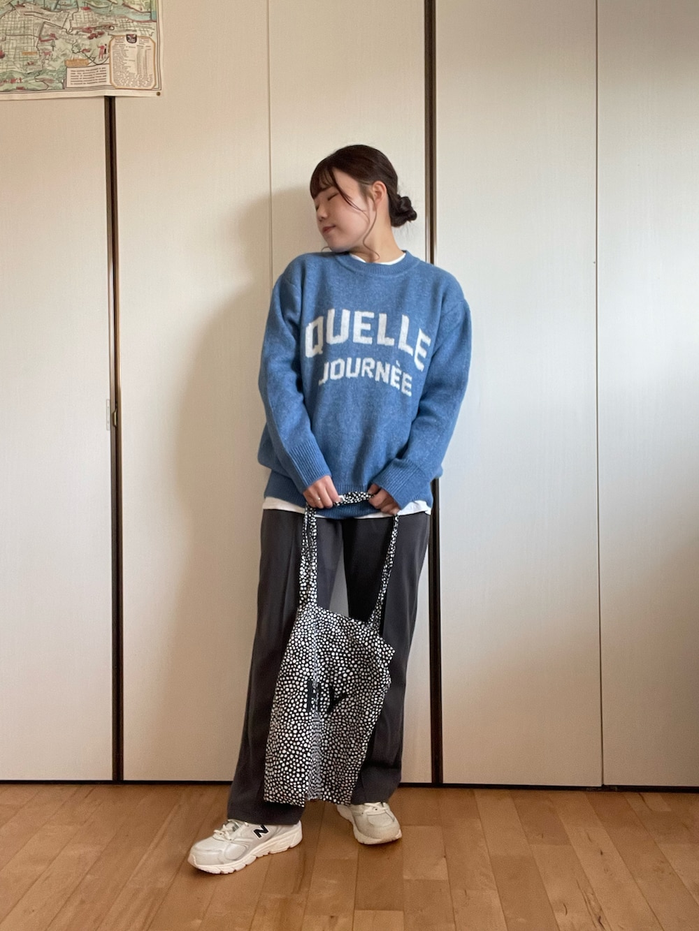 ブルー系のニット/セーター、ブラック系のトートバッグ、グレー系のスラックスを着用したレディースの冬コーディネートの2枚目の写真