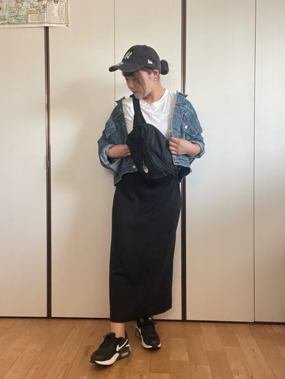 ブラック系のスニーカー、ブラック系のショルダーバッグ、ブラック系のスカートを着用したレディースの秋コーディネートの2枚目の写真