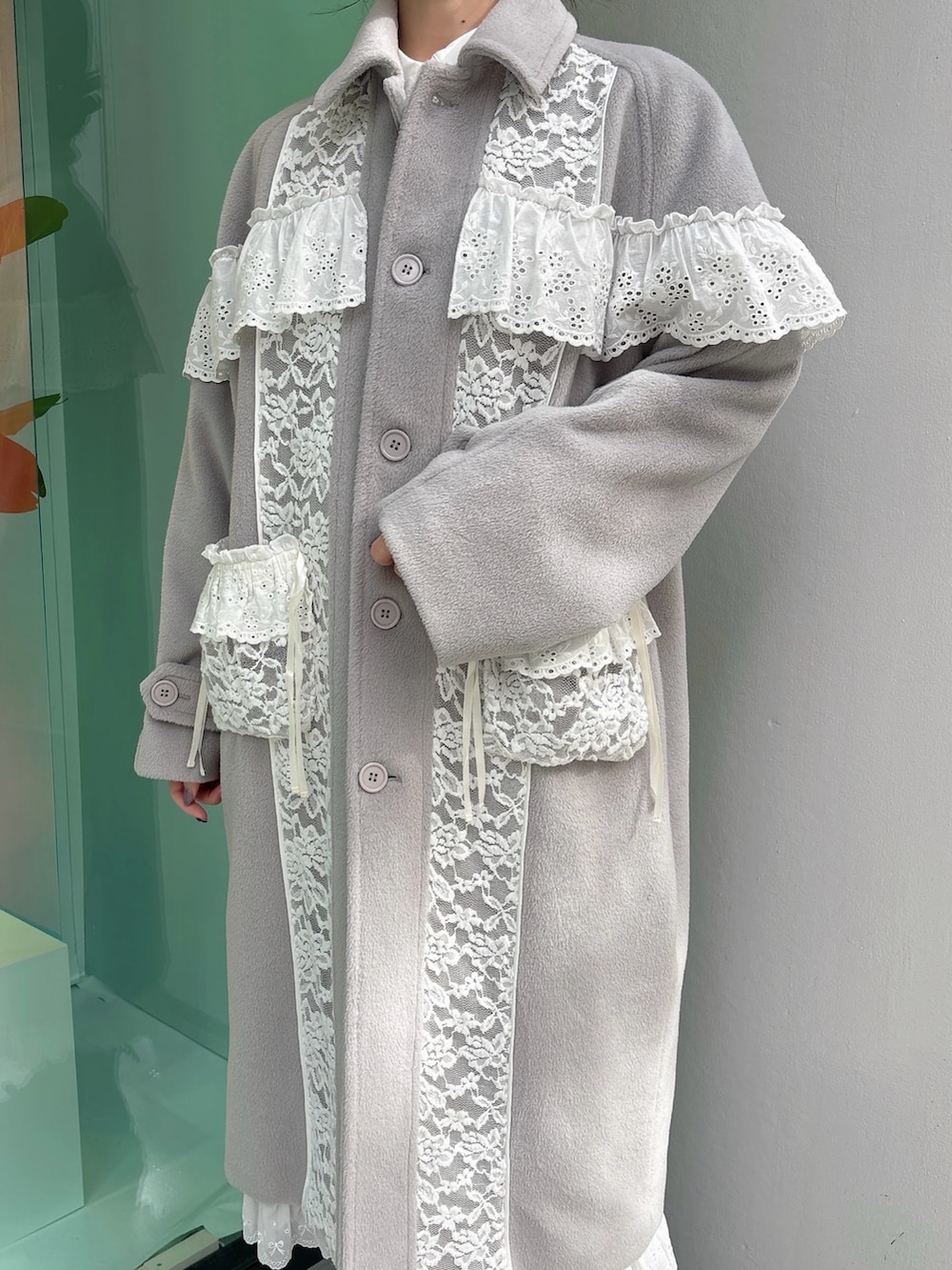 グレー系のチェスターコート、ベージュ系のショルダーバッグ、ホワイト系のワンピースを着用したレディースの秋コーディネートの5枚目の写真