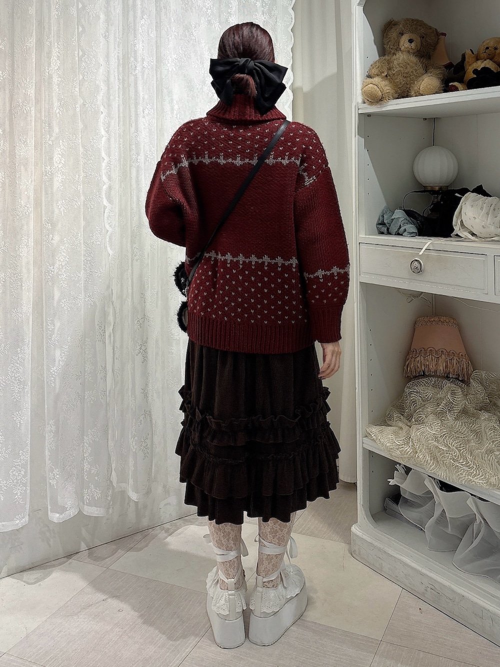 ブラウン系のスカート、ブラック系のショルダーバッグ、ホワイト系のスニーカーを着用したレディースの秋コーディネートの2枚目の写真