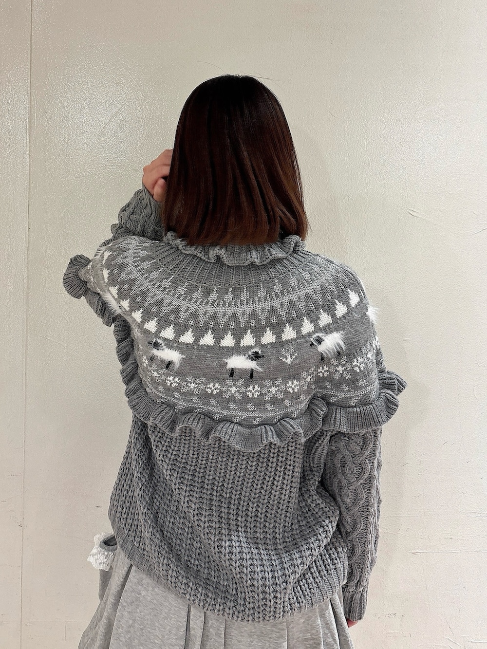 グレー系のニット/セーター、グレー系のスカート、ホワイト系のその他パンツを着用したレディースの冬コーディネートの4枚目の写真