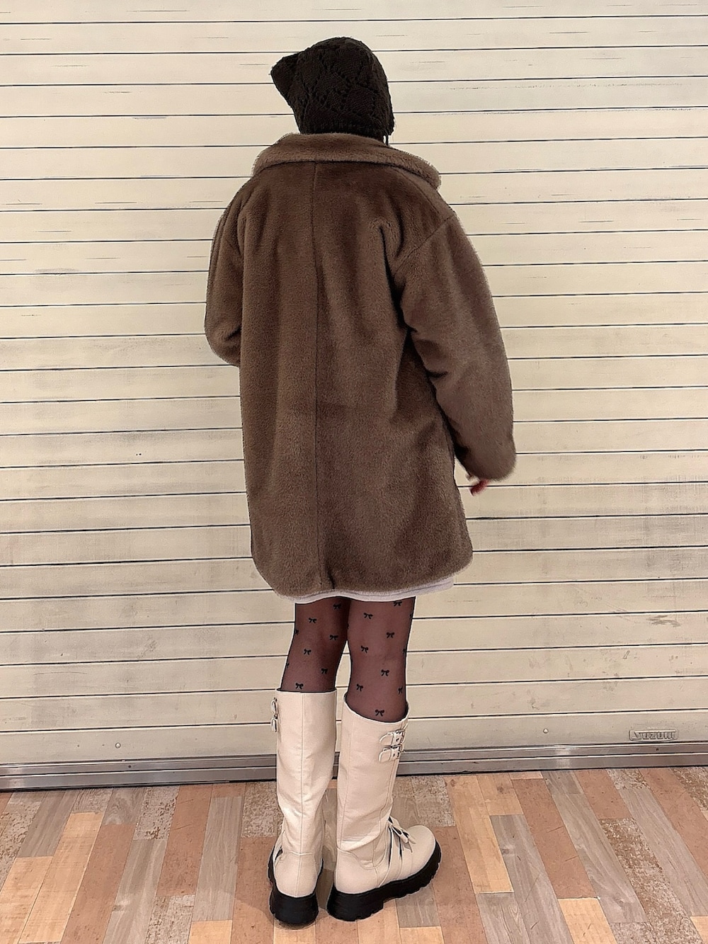 グレー系のニット/セーター、ブラウン系のノーカラーコート、ブルー系のワンピースを着用したレディースの冬コーディネートの2枚目の写真
