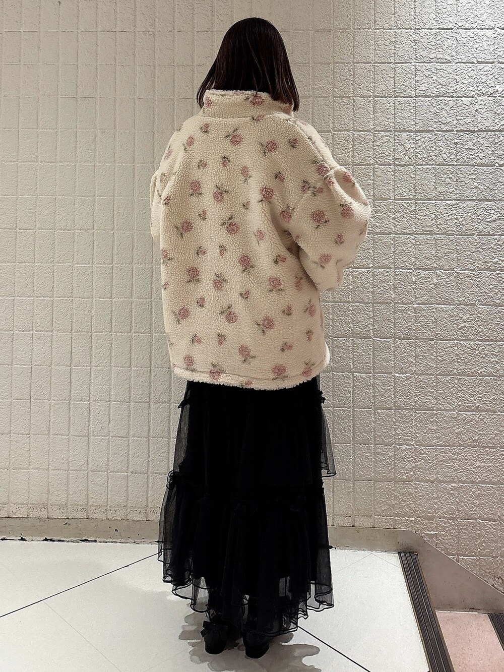 ピンク系のブルゾン、ホワイト系のニット/セーター、ブラック系のスカートを着用したレディースの冬コーディネートの2枚目の写真