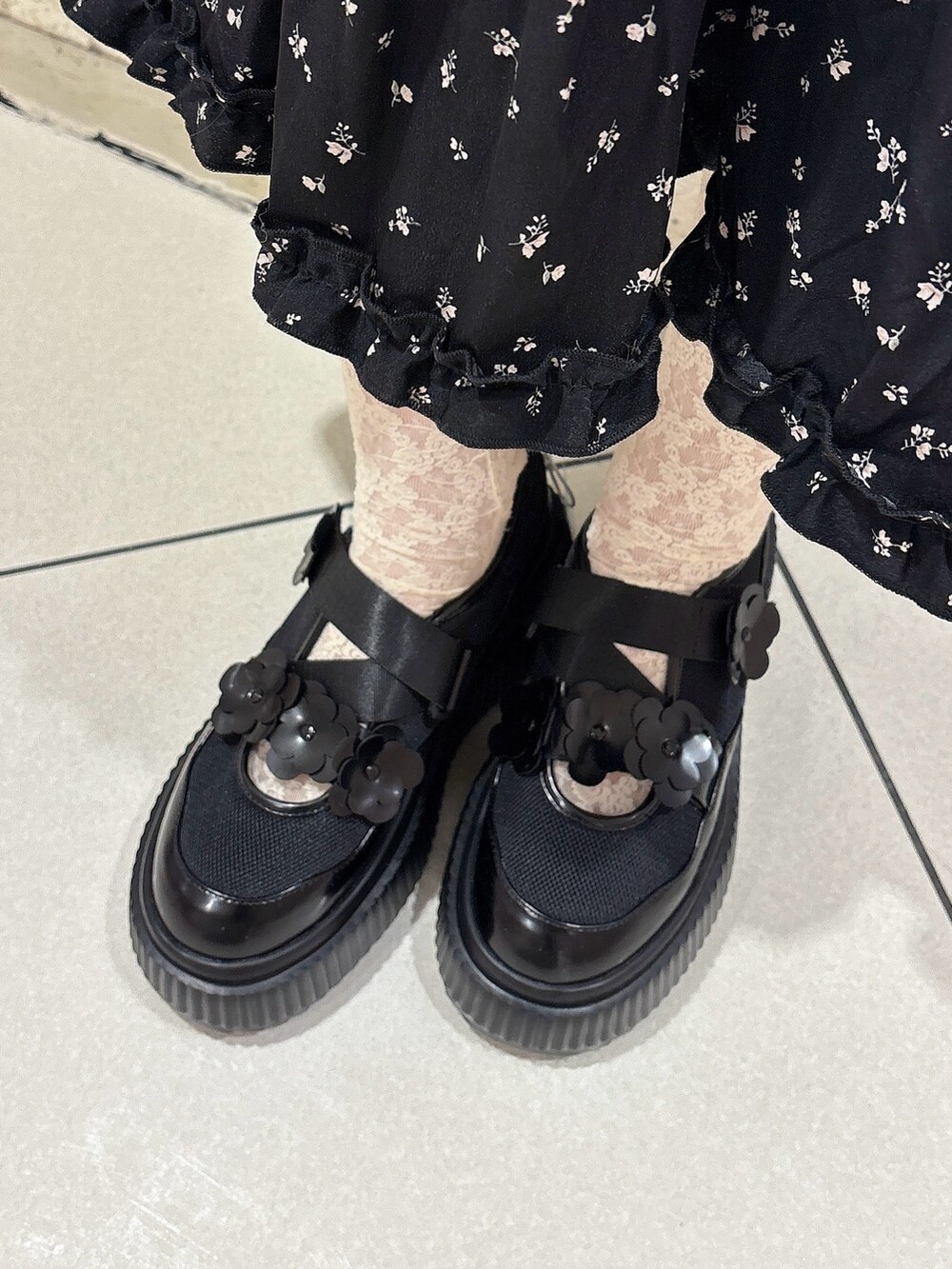 ブラック系のワンピース、ホワイト系のカーディガン/ボレロ、ブラック系のスニーカーを着用したレディースの冬コーディネートの6枚目の写真