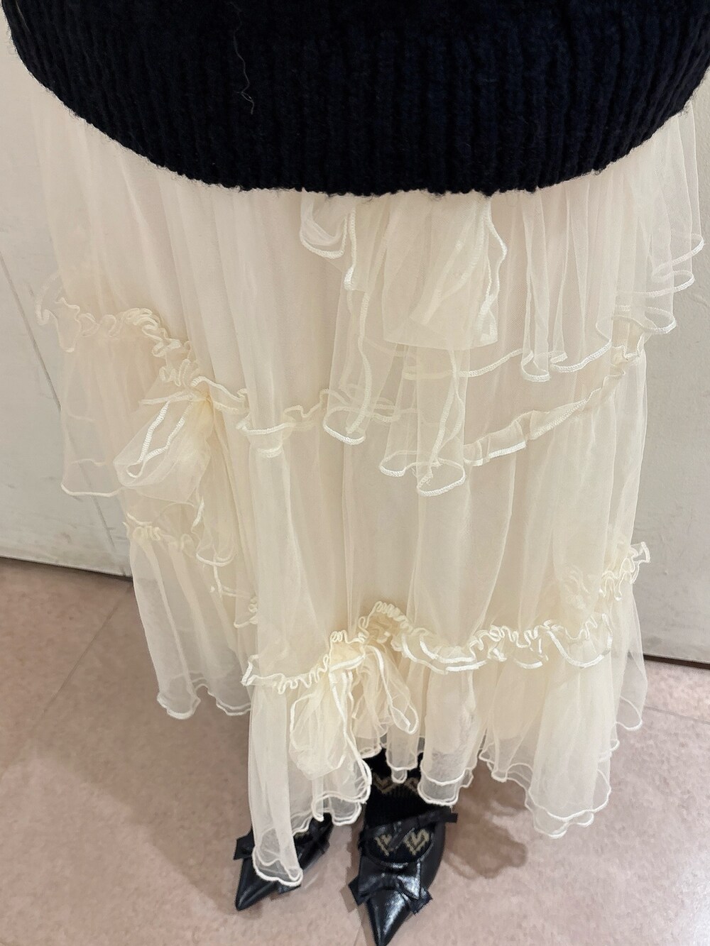 ブラック系のニット/セーター、レッド系のショルダーバッグ、ホワイト系のスカートを着用したレディースの冬コーディネートの7枚目の写真