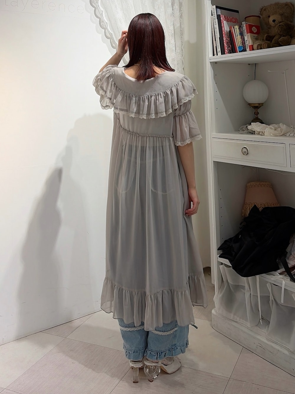 グレー系のワンピース、ホワイト系のキャミソール、ブルー系のデニムパンツを着用したレディースの春コーディネートの2枚目の写真