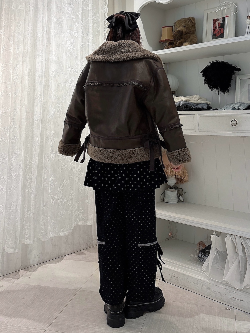 ブラウン系のムートンコート、パープル系のニット/セーター、ブラック系のスカートを着用したレディースの秋コーディネートの2枚目の写真